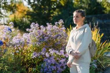 Sonbaharda bir parkta duran zarif bir kadın. Sonbahar sarı yaprakları. Sonbaharda parkta neşeli bir kadının portresi. Sarı yapraklı mutlu kız. Güzel, romantik kız dışarıda eğleniyor.