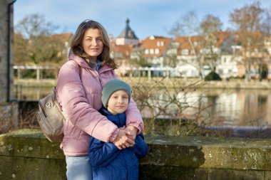 Riverside Aile Uyumu: Anne, 30 yaşında ve Oğul - 8 yaşında güzel bir çocuk, Neckar Nehri kıyısında ve Tarihi yarım kereste kasabası, Bietigheim-Bissingen, Almanya, Autumn. Kendini batır.