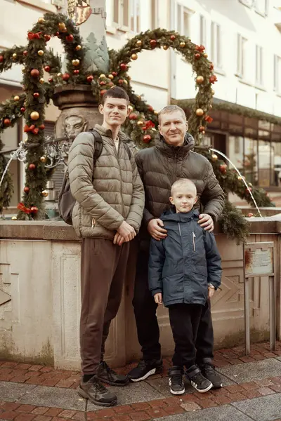 stock image Joyful Family Portrait: Father and Two Sons by Festive Vintage Fountain. Capture the essence of familial happiness with this heartwarming image featuring a handsome father with his two sons standing