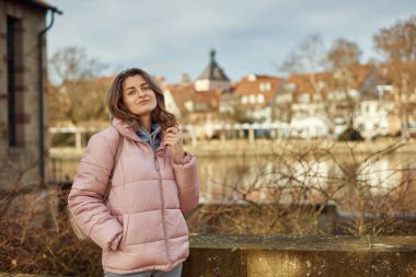 Avrupa 'da soğuk bir sonbaharda sırt çantalı, kalın şapkalı ve ceketli güzel bir turist kız Zürih İsviçre' ye seyahatinin tadını çıkarıyor. Genç turist kadının açık hava portresi.