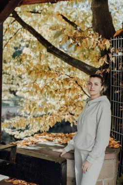 Sonbaharda bir parkta duran zarif bir kadın. Sonbahar sarı yaprakları. Sonbaharda parkta neşeli bir kadının portresi. Sarı yapraklı mutlu kız. Güzel, romantik kız dışarıda eğleniyor.