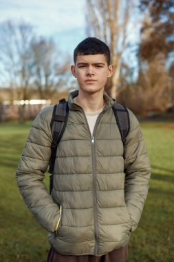 Gençlik Zarafeti: 17 yaşında, Güz Parkı 'nda Lush Green Lawn ile duran güzel bir çocuk. Seyircilerinizi, 17 yaşında güzel bir oğlanın yer aldığı bu görüntünün zarifliğiyle büyüleyin.