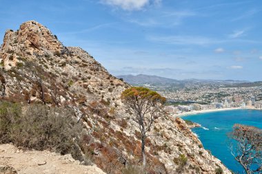 İspanya 'nın çarpıcı Calpe Körfezi' ne bakan kayalıklardan nefes kesici bir manzara berrak suları, kumlu plajları ve parlak mavi gökyüzü altında görkemli kaya oluşumları..