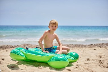 İdealist Aile Kaçamağı: Neşeli Çocuk Altın Kumlar ve Huzurlu Okyanus Dalgaları Ortasında Kaplumbağa Şeklinde Yüzüyor
