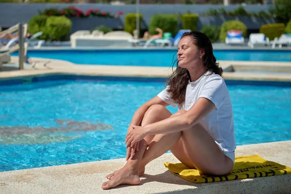 stock image Tropical Paradise Retreat: Carefree Woman Enjoying Sun-Soaked Relaxation at Exclusive Mediterranean Resort Pool Mediterranean Bliss: Young Woman Relaxing Poolside at Luxurious Resort Under Swaying