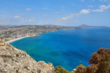 İspanya 'nın çarpıcı Calpe Körfezi' ne bakan kayalıklardan nefes kesici bir manzara berrak suları, kumlu plajları ve parlak mavi gökyüzü altında görkemli kaya oluşumları..