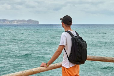 Cesur Erkek Gezgin Dramatik Uçurumda Güzelliği Kucaklayan Gökyüzü Suları Sportif Güneş gözlükleri ve Sırt çantası