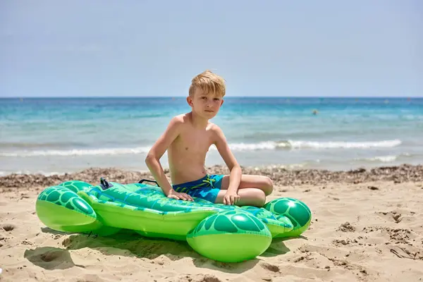 stock image Idyllic Family Getaway: Joyful Boy Lounging on Whimsical Turtle-Shaped Float Amidst Golden Sands and Tranquil Ocean Waves