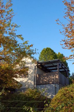 Büyüleyici bir köy evi, berrak mavi gökyüzünün altında canlı, renkli sonbahar ağaçları arasında güzelce yuva yapar.