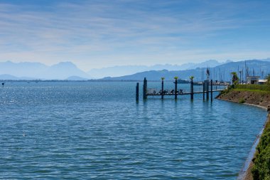 Germany, Lindau island city houses at bodensee lake water panorama view to austrian mountains, alps, pfaender peak and nature landscape. clipart