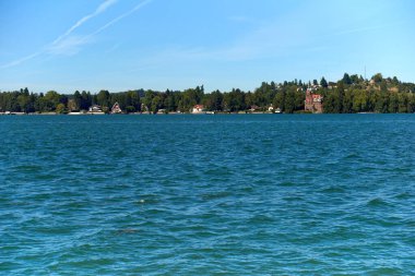 Constance Bodensee Gölü 'nün sakin şeffaf suları ve arka planda İsviçre Alpleri, Almanya' nın Lindau adasında sakin bir Ekim günü. Bu çarpıcı görüntü Lindau 'nun özünü yakalar.