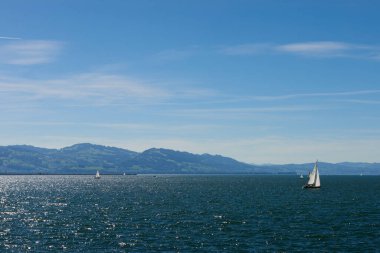 Bodensee 'nin nefes kesici Panorama' sı. Beyaz yelkenliler ve Lindau, Almanya 'dan İsviçre Alpleri. Idyllic Yaz Sahnesi Avrupa Tatil Cenneti Şovu Yelkencilik, Doğa ve Dağ Vistalarını Yakalıyor