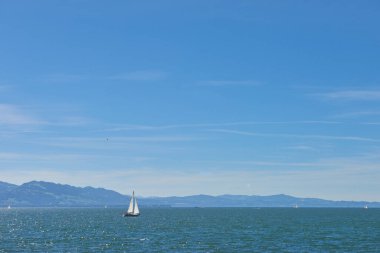 Bodensee 'nin nefes kesici Panorama' sı. Beyaz yelkenliler ve Lindau, Almanya 'dan İsviçre Alpleri. Idyllic Yaz Sahnesi Avrupa Tatil Cenneti Şovu Yelkencilik, Doğa ve Dağ Vistalarını Yakalıyor