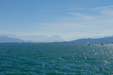 Bodensee 'nin nefes kesici Panorama' sı. Beyaz yelkenliler ve Lindau, Almanya 'dan İsviçre Alpleri. Idyllic Yaz Sahnesi Avrupa Tatil Cenneti Şovu Yelkencilik, Doğa ve Dağ Vistalarını Yakalıyor