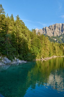 Bu nefes kesici görüntü, Eibsee 'nin dingin güzelliğini gözler önüne seriyor. Zugspitze' nin eteklerinde, Almanların en yüksek tepesinde kurulmuş bir alp gölü. Gölün berrak suları mükemmel bir şekilde yansıyor.