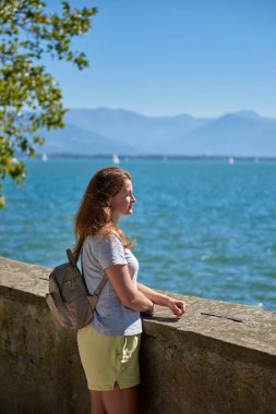 Bu büyüleyici görüntüde Constance Bodensee Gölü 'nün köpüklü sularında duran muhteşem bir kız gölün karşısındaki Alplerin nefes kesici dağ manzarasına bakıyor. Parlak