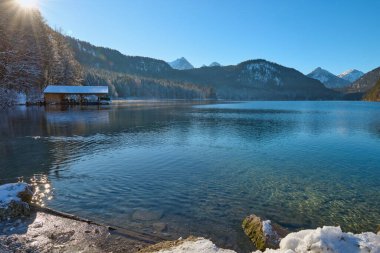 Huzurlu Kış Harikalar Diyarı: Donmuş Göl, Altın Sabah Donmuş Dağları Yansıtır. Buz gibi buzlu manzaralar, Kıtır Güneşli bir günde Alp Gölü 'nün nefes kesici güzelliğini yakalar. Bu büyüleyici görüntü, sakin bir kış manzarasını gözler önüne serer.