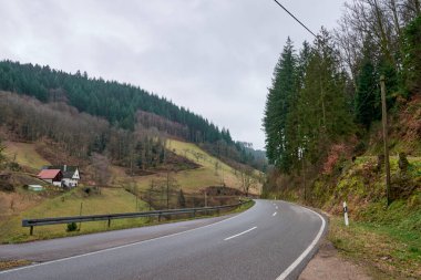 Modern otobanın geleneksel dağlık bölgede dolaştığı güzel dağ vadisi manzarası. Kırsal kesimde kendine özgü kırmızı çatıları olan geleneksel beyaz evler sergileniyor