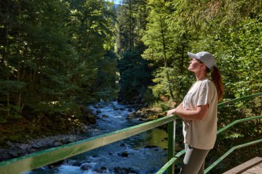 Yazın Alplerde Yürüyüş Yolu 'nda Manzaralı Dağ Nehri Manzarası İzleyen Çarpıcı Genç Kadın. Idyllic Alpine Manzarası Açık Hava Macerası ve Doğal Güzelliğin Özünü Yakalıyor. Bu...