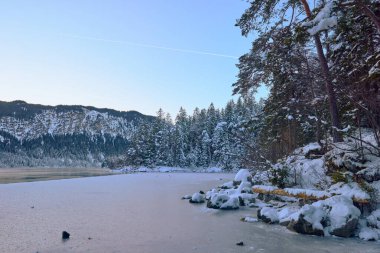 Büyüleyici Alacakaranlık Alp Harikalar Diyarı: Eibsee Gölü Kar Kaplamalı Zugspitze Dağı 'nı Aydınlatılmış Çam Ormanı' nın ortasında Yansıtır Kış Büyüleyici Manzarası Alman Kayak Resimlerinin Huzurlu Güzelliğini Yakalar