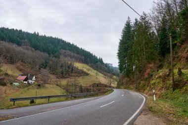Modern otobanın geleneksel dağlık bölgede dolaştığı güzel dağ vadisi manzarası. Kırsal kesimde kendine özgü kırmızı çatıları olan geleneksel beyaz evler sergileniyor