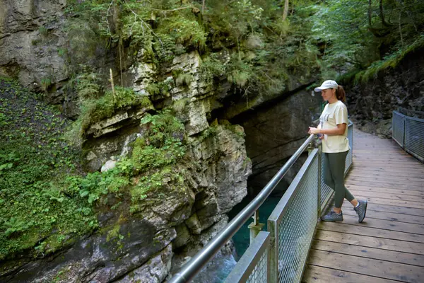 Yazın Alplerde Yürüyüş Yolu 'nda Manzaralı Dağ Nehri Manzarası İzleyen Çarpıcı Genç Kadın. Idyllic Alpine Manzarası Açık Hava Macerası ve Doğal Güzelliğin Özünü Yakalıyor. Bu büyüleyici görüntüde genç ve güzel bir kadın var.