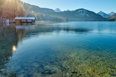 Huzurlu Kış Harikalar Diyarı: Donmuş Göl, Altın Sabah Donmuş Dağları Yansıtır. Buz gibi buzlu manzaralar, Kıtır Güneşli bir günde Alp Gölü 'nün nefes kesici güzelliğini yakalar. Bu büyüleyici görüntü, sakin bir kış manzarasını gözler önüne serer.