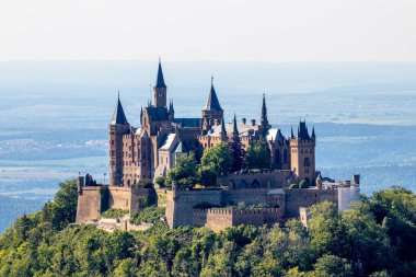 Hohenzollern Şatosu ormanın önü ve mavi gökyüzü ile çevrili