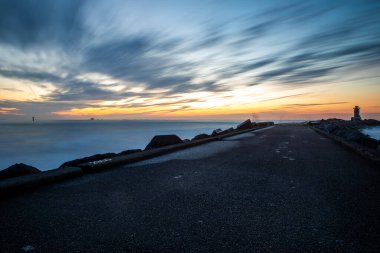 path to lighthouse on zuidpier IJmuiden at blue hour with cloudy sky at blue hour long exposure