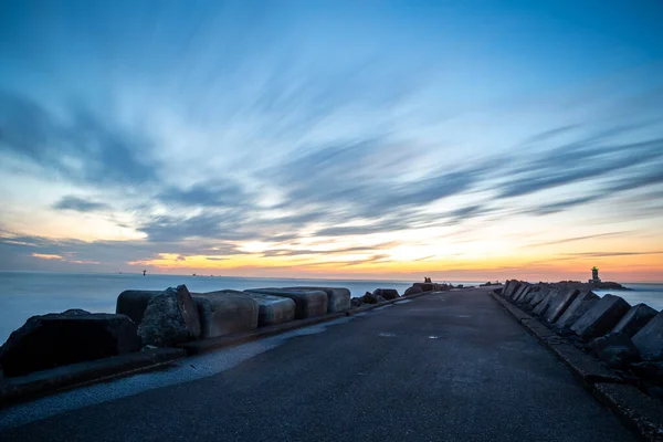 path to lighthouse on zuidpier IJmuiden at blue hour with cloudy sky at blue hour long exposure
