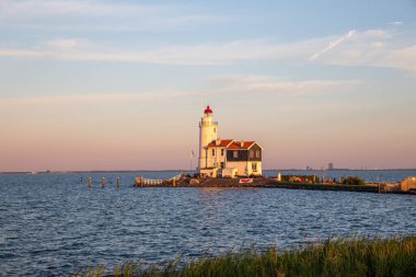 paard van marken lighthouse on marken island in golden hour with blue sky and sea with grass in foreground