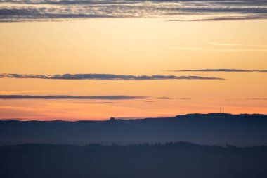 dawn with red orange sky before sunrise in germany swabia with hohenzollern castle at the horizon