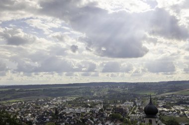 Herrenberg, tarihi binalar ve doğal manzaraların çarpıcı bir karışımını sergiliyor. Fotoğraf şehrin büyüleyici çatılarını bulutlu bir gökyüzünün altında yakalıyor, yemyeşil ile çevrili..