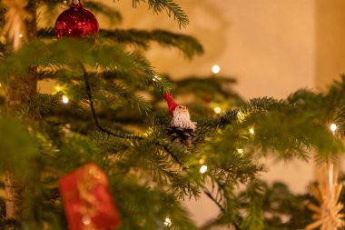 Renkli süsler ve sıcak ışıklar güzel dekore edilmiş bir Noel ağacını güzel bir oturma odasında aydınlatarak tatil sezonu için şenlikli bir atmosfer yaratıyor..