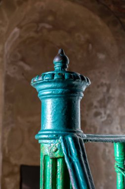 Karmaşık yeşil çelik parmaklık tasarım elementleri zengin bir tarihi ortaya koyuyor. Yıpranmış çevreyle canlı renkler zıtlaşır