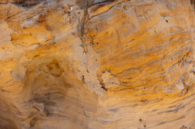 Kayalık bir yüzeye yakın çekim yapmak karmaşık dokuları ve sıcak renkleri ortaya çıkarır. Doğal ışık eşsiz oluşumları vurgular, sakin bir ortamda jeolojinin güzelliğini gösterir..