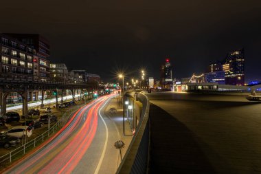Renkli ışık yolları Hamburg 'daki yoğun trafiği gösteriyor. İkonik binalar yayalar rıhtım boyunca canlı atmosferin tadını çıkarırken parlak bir şekilde parlıyor..