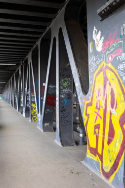 Hamburg 'daki canlı bir alt geçit, şehrin yaratıcılığını vurgulayarak, yayalar kirişlerin altında yürürken, yapısal desteklerinde benzersiz graffiti sanatını sergiliyor..