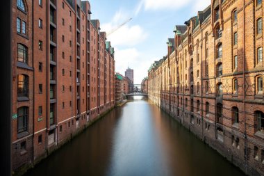 Tarihsel tuğla depoları Speicherstadt Hamburg, Almanya 'daki kanalın sakin suyunu yansıtır. Sahne, şehrin mimarisinin cazibesini açık bir gökyüzü altında yakalıyor..