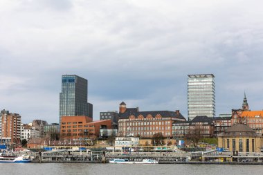 Hamburg 'un Skyline' ında nehir kıyısında modern gökdelenler ve tarihi yapılar yer almaktadır. Rıhtım boyunca yaşanan hareketlilik, insanların şehrin tadını çıkarmasını içeriyor..