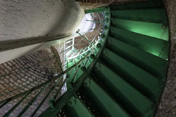 Çelikten yapılmış sarmal yeşil merdiven. Görünür tuğlalardan yapılmış eski binanın içi.