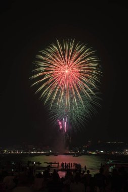 İnsanlarla dolu renkli havai fişekler ve deniz kenarındaki gece lambaları kutlamaları..