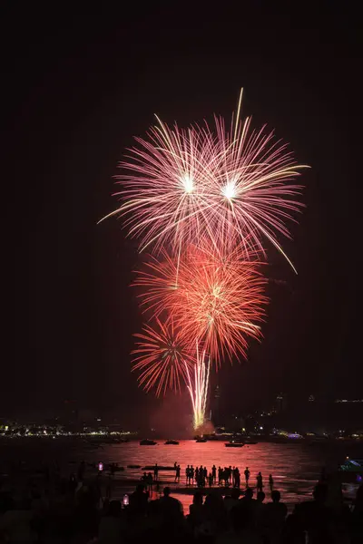 İnsanlarla dolu renkli havai fişekler ve deniz kenarındaki gece lambaları kutlamaları..