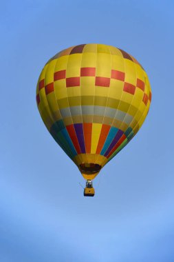 Parlak güneş ışığında mavi gökyüzünün üzerinde renkli sıcak hava balonu.