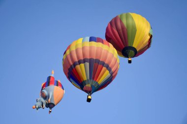 Parlak güneş ışığında mavi gökyüzünün üzerinde renkli sıcak hava balonu.