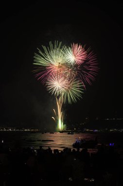 İnsanlarla dolu renkli havai fişekler ve deniz kenarındaki gece lambaları kutlamaları..