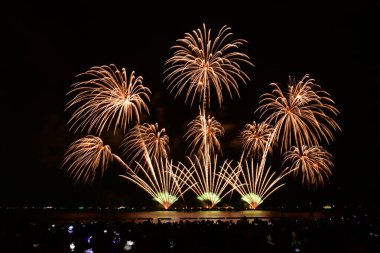 Renkli bir havai fişek kutlaması ve deniz kenarında gece lambaları. Pattaya, Tayland 'da uluslararası havai fişek festivali.