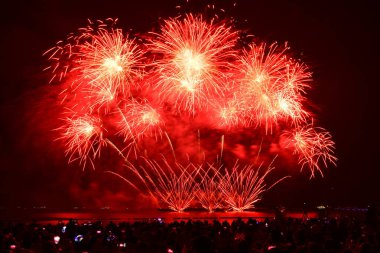 Renkli bir havai fişek kutlaması ve deniz kenarında gece lambaları. Pattaya, Tayland 'da uluslararası havai fişek festivali.
