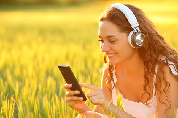 Ευτυχισμένη Γυναίκα Ένα Πεδίο Ακούγοντας Μουσική Χρησιμοποιώντας Τηλέφωνο Στο Ηλιοβασίλεμα — Φωτογραφία Αρχείου
