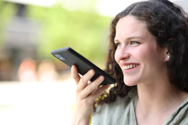 スマートフォンで音声認識を使って路上を歩く幸せな女性 — ストック写真